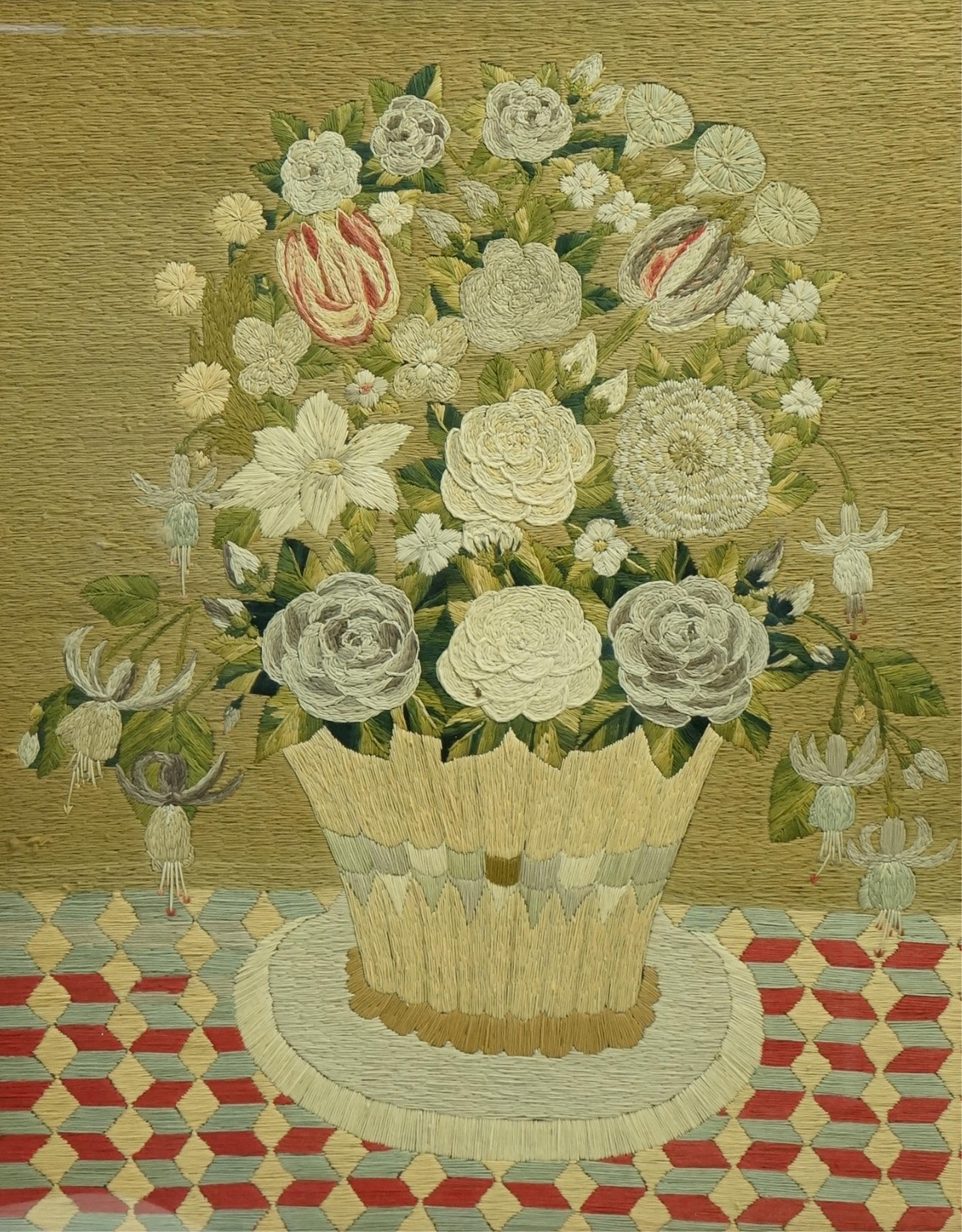A large maple framed 19th century wool worked still life embroidery of a vase flowers on a check patterned cloth, worked in stem stitch and then over stitched in places to give depth. 48cm wide x 60.5cm high. Condition -